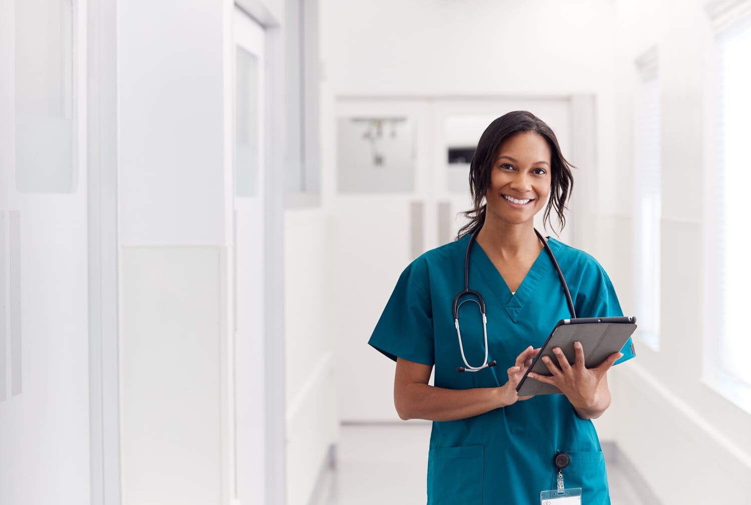 Portrait,Of,Smiling,Female,Doctor,Wearing,Scrubs,In,Hospital,Corridor